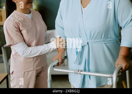 Krankenschwester hilft reifer afroamerikanischer Patientin, mit Hilfe von Gehhilfen für Senioren zu gehen Stockfoto