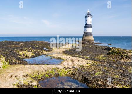Leuchtturm am Rande einer felsigen Landzunge. Der Leuchtturm befindet sich in Penmon Point, Angelsey, Nordwales. Der Tag ist sonnig Stockfoto