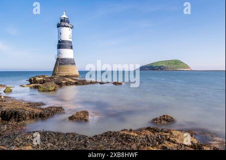 Leuchtturm am Rande einer felsigen Landzunge. Der Leuchtturm befindet sich in Penmon Point, Angelsey, Nordwales. Der Tag ist sonnig Stockfoto