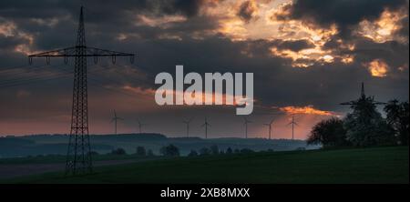 Ein Schuss von Stromleitungen, die vor einem Sonnenuntergang in der ländlichen Landschaft stehen Stockfoto