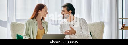 Ein bärtiger Mann und eine rothaarige Frau führten ein tiefes Gespräch, während sie bequem auf einer modernen Couch in einer gemütlichen Wohnung saßen. Stockfoto