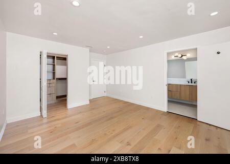Ein gemütliches Schlafzimmer mit Holzfußboden und weißen Wänden, mit mehreren Eingängen Stockfoto
