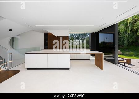 Offene Küche mit weißer Theke, Holzregalen und Türen Stockfoto