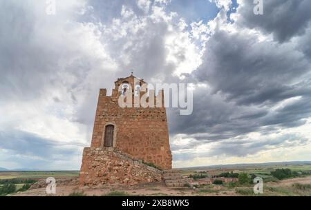 Weitwinkelblick auf den Martina-Turm im Vordergrund, mit der mittelalterlichen Stadt Ayllon unter einem bewölkten Himmel. Stockfoto