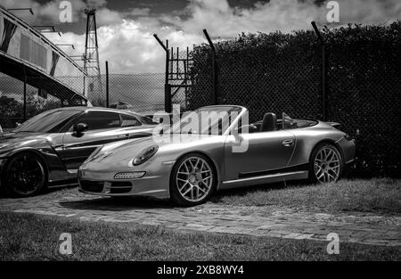 Zwei silberne Autos parken an einem Zaun Stockfoto