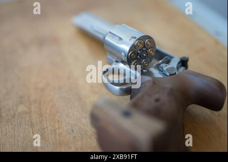 Detail der Trommel eines Revolvers mit Kugeln. Es gibt viel Bokeh und die Waffe steht auf einem Holztisch. Kaliber 357 Magnum oder .38 Special Stockfoto