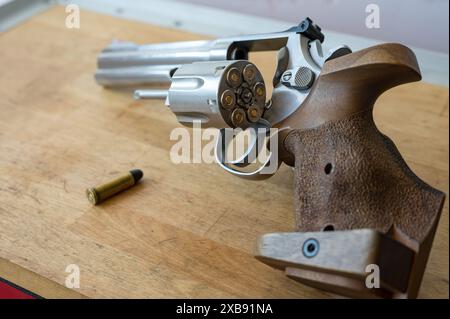 Trommel eines Revolvers voller Kugeln. Die Waffe steht auf einem Holztisch. Daneben befindet sich eine Kugel des Kalibers .357 Magnum oder .38 Special Stockfoto