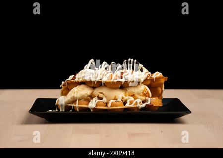 Ein Eisdessert in Waffeln auf einem schwarzen Teller Stockfoto