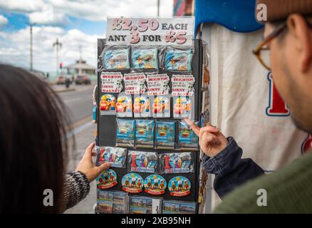 Touristen halten an, um farbenfrohe Kühlschrankmagnete zu kaufen, die traditionelle britische Küstenansichten auf Brighton in East Sussex, Großbritannien, zeigen Stockfoto