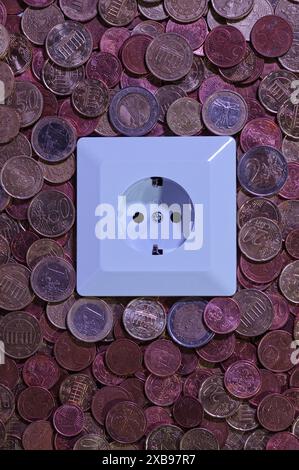 Nahaufnahme einer Steckdose vor dem Hintergrund verschiedener Euro-Münzen. Stockfoto