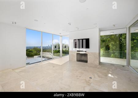 Ein geräumiges Wohnzimmer mit Panoramablick auf Bäume und Berge durch große Fenster Stockfoto