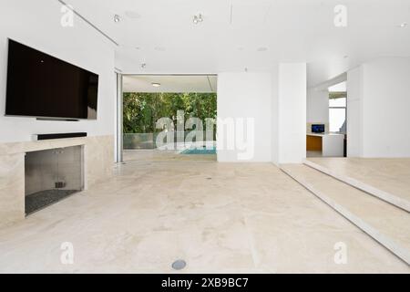 Ein modernes Wohnzimmer mit weißen Möbeln, Kamin und Flachbildfernseher Stockfoto