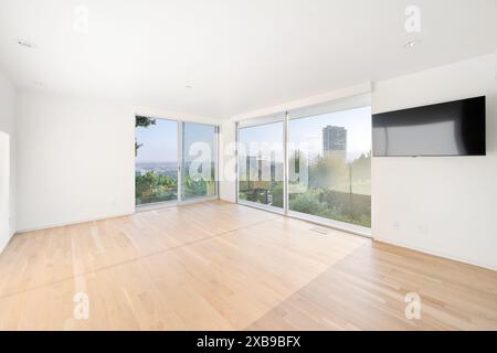 Ein Wohnzimmer mit einer breiten Glasschiebetür, die sich zu einem Blick auf die Stadt öffnet Stockfoto