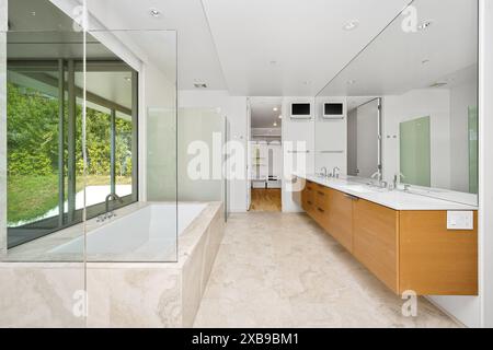 Modernes Bad mit zwei Waschbecken, Badewanne am Fenster und offener Tür Stockfoto