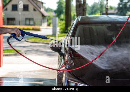 Manuelle Waschanlage mit unter Druck stehendem Wasser in der Waschanlage im Freien. Autowäsche Im Sommer. Stockfoto