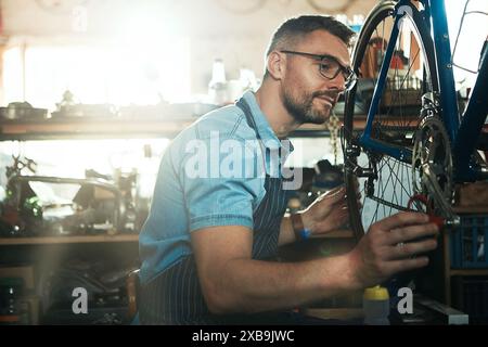Mann, Garage und ernsthaft als Fahrradmechaniker mit Linsenfackeln in Startup oder Kleinunternehmen. Werkstatt, Werkzeuge und selbstbewusst als Handwerker mit Reparatur-Motorrad Stockfoto