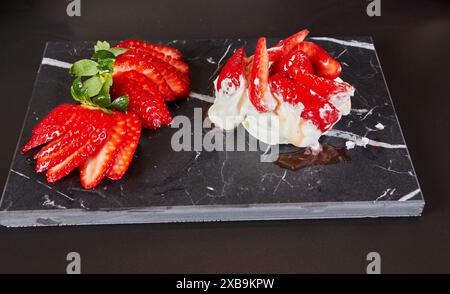 Ein Hauskoch bereitet Meringue zu, legt Erdbeeren auf im Ofen gebackene Meringue. Stockfoto