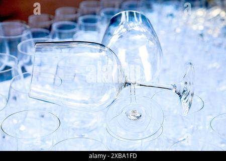 Zwei Rotweinkristallgläser lagen auf einem Rohbau anderer Gräser, die für eine große Party vorbereitet wurden. Verschwommen. Catering und Restaurant Utensilien. Hochzeitsorganisation Stockfoto