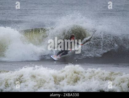 Gilgo Beach, New York, USA - 30. August 2023: Ein männlicher Surfer surft im Regen mit Hurrikan Franklin vor der Küste von Long Island. Stockfoto