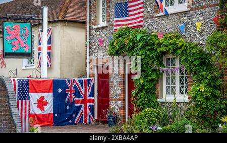 Nationalflaggen zum Gedenken an den D-Day hängen vor einem Puberhaus in Southwick Village, Hampshire. Stockfoto