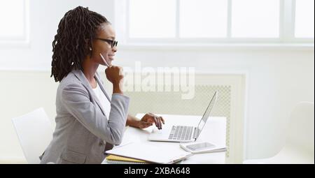Frau in Brille, die im Büro auf dem Laptop schreibt Stockfoto
