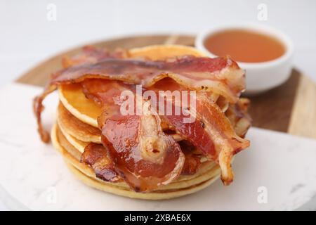 Leckere Pfannkuchen mit Speck und Honig auf weißem Tisch, Nahaufnahme Stockfoto