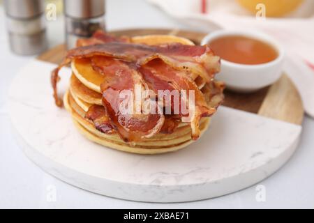 Leckere Pfannkuchen mit Speck und Honig auf weißem Tisch, Nahaufnahme Stockfoto