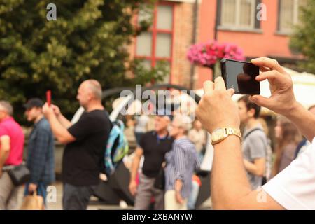 Halten Sie das Telefon in der Hand, und machen Sie Fotos, und reisen Sie Erinnerungen. Machen Sie ein Foto, halten Sie das Telefon, Reiseerinnerungen. Verschwommener Sommer-Hintergrund der Stadt. Stockfoto
