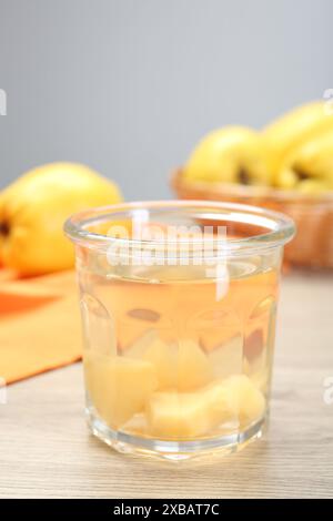 Köstliches Quittengetränk im Glas und frisches Obst auf Holztisch, Nahaufnahme Stockfoto