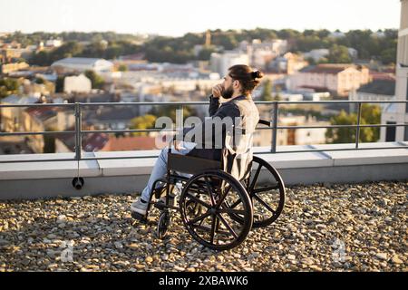 Mann im Rollstuhl mit Blick auf die Stadt auf dem Dach Stockfoto