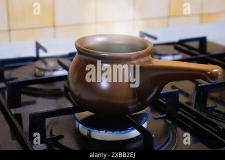 Türkischer Kaffee in einem keramischen Türken auf einem Gasherd zubereiten. Türkischer Kaffee auf dem Herd in Nahaufnahme. Stockfoto