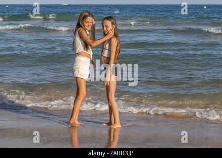 Dieses Bild fängt einen zärtlichen Moment ein, den zwei wunderschöne Zwillingsschwestern mit langen blonden Haaren und grünen Augen während ihres Urlaubs teilen. Stockfoto