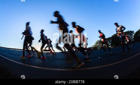 Die Bewegungsgeschwindigkeit von Marathonläufern verwischt die Silhouette des Sonnenaufgangs am Morgen, der in Ultra-Distanz bergauf läuft Stockfoto