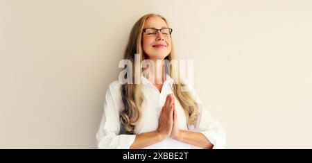Ruhige entspannende gesunde Frau mittleren Alters meditiert und übt Yoga auf weißem Studio Hintergrund Stockfoto