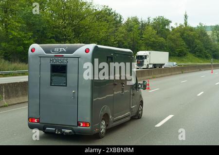 Lyon, Frankreich - 16. Mai 2023: Ein Pferdeanhänger mit PFERDEN fährt die Autobahn entlang, umgeben von üppigem Grün neben der Straße. Stockfoto