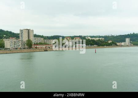 Vienne, Frankreich - 16. Mai 2023: Panoramablick auf die Rhone in Vienne, Frankreich, mit Wohnhäusern und grünen Hügeln im Hintergrund. Stockfoto