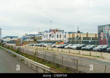 Vienne, Frankreich - 16. Mai 2023: Eine große Aufnahme eines großen Industriegebäudes mit einer Reihe geparkter Autos davor. Eine große Werbetafel mit einem jungen Giganten Stockfoto