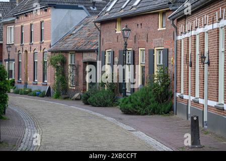 Eine ruhige Dorfstraße mit Reihen alter Backsteinhäuser, Fensterläden und gepflegten Hecken, Bredevoort, Gelderlande, niederlande Stockfoto