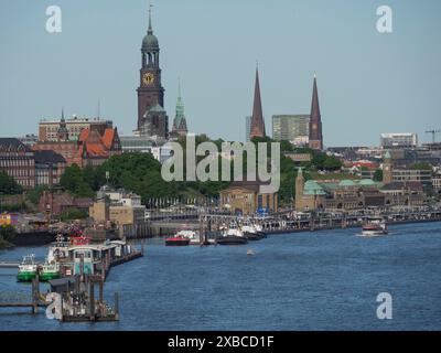 Blick auf die Stadt mit mehreren Kirchtürmen und Booten entlang eines Flusses unter blauem Himmel, Elbe, Hamburg, Norddeutschland, Deutschland Stockfoto