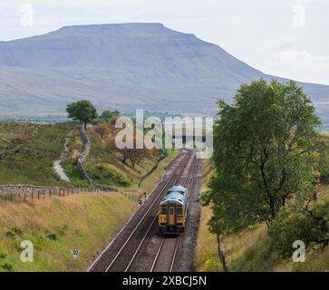 Dieselzug der Northern Rail Class 158 nähert sich dem Blea Moor Tunnel auf der Siedlung nach Carlisle Railway, Yorkshire, Großbritannien. Ingleborough ist im Rückstand Stockfoto