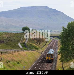 Dieselzug der Northern Rail Class 158 nähert sich dem Blea Moor Tunnel auf der Siedlung nach Carlisle Railway, Yorkshire, Großbritannien. Ingleborough ist im Rückstand Stockfoto