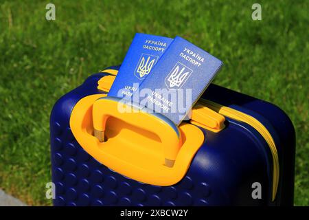 2 Pässe ukrainische Staatsbürger mit Inschrift auf Ukrainisch - Reisepass der Ukraine liegen auf gelb blauem Koffer in der Farbe der ukrainischen Flagge. Reisen, Zuflucht Stockfoto