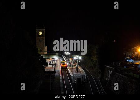 Erster TransPennine Express Siemens-Zug der Baureihe 185 185124 am Bahnhof Ulverston mit dem Uhrenturm in der Nacht Stockfoto