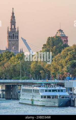 Ein Kreuzfahrtschiff legte auf dem Guadalquivir-Fluss an, mit der Alamillo-Brücke und der Giralda im Hintergrund, Sevilla, Spanien. Stockfoto