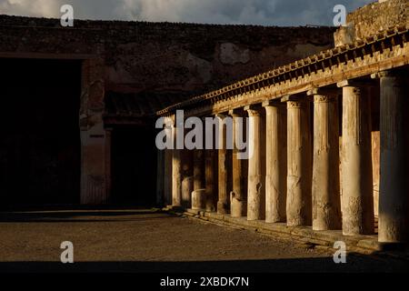 Antike römische Kolonnade, Säulen, die in den goldenen Tönen des Sonnenuntergangs getaucht sind. Pompeji, Italien. Stockfoto