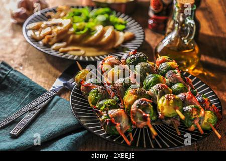 Spieße mit frischem Rosenkohl und Speck auf dem Tisch - dunkel und stimmungsvoll Stockfoto