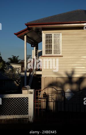 Vorstadt-Nachkriegswetterhaus, Frontzaun, Palmenschatten, Flügelfenster opak strukturierte Glasfenster in voller Sonne, Carina, Brisbane Stockfoto