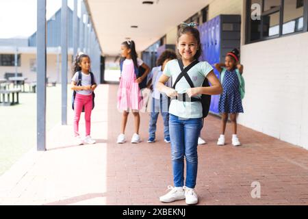 Birassische Schüler stehen vor dem Schulgebäude, tragen Rucksäcke und lächeln Stockfoto