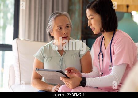 Asiatische Seniorin berät junge asiatische weibliche Gesundheitsberaterin zu Hause. Gesundheitswesen, Seniorenleben, Ruhestand, Hilfe zu Hause, Besuch, unaltere Stockfoto