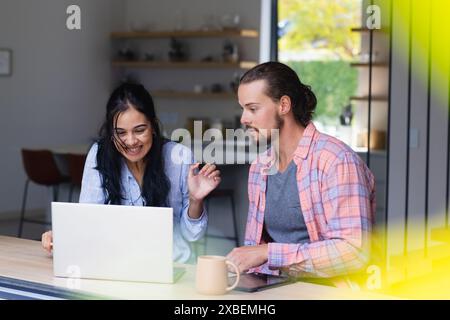 Ein junges, vielseitiges Paar sieht sich zusammen einen Laptop an Stockfoto